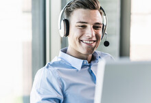 Close-up Of Smiling Businessman Talking Over Headset In Call Center