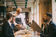 © Maskot - Waiter showing menu to business people in restaurant