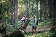 © Maskot - Side view of daughter climbing log by father in forest