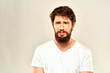 © SHOTPRIME STUDIO - A man in a white t-shirt with a beard emotions displeased facial expression light background