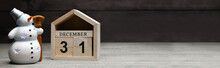 Christmas Decorations On A Wooden Background: Wooden Cubes With The Numbers December 31 And A Glowing Snowman, Empty Space For Text On The Right. Selective Focus. Banner.