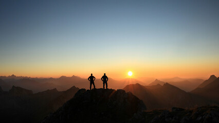 Poster - Two Men reaching summit enjoying freedom and looking towards mountains sunset.