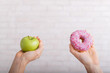 © Михаил Решетников - Donut and green apple in female hands. The concept of different eating habits. Thinness and obesity