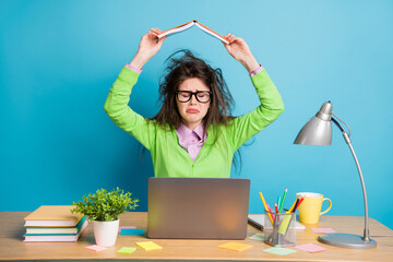 Sticker - Portrait of her she nice frustrated brunette girl holding book over head like roof crying isolated over vibrant blue color background