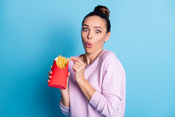 Sticker - Photo of astonished girl eat takeout crispy french fries impressed junk food delicious snack wear lilac pullover isolated over blue color background