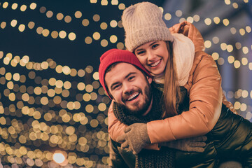 Sticker - Photo of bonding couple boyfriend piggyback girlfriend under x-mas tradition christmas outside evening illumination wear season coats scarf headwear