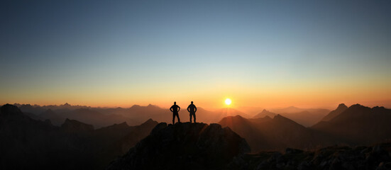 Aufkleber - Two Men reaching summit enjoying freedom and looking towards mountains sunset.