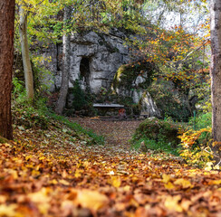 Wall Mural - Statue of Virgin Mary in the rock in autumn forest