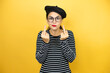 © Irene - Young beautiful brunette woman wearing french beret and glasses over yellow background showing middle finger doing fuck you bad expression, provocation and rude attitude. screaming excited