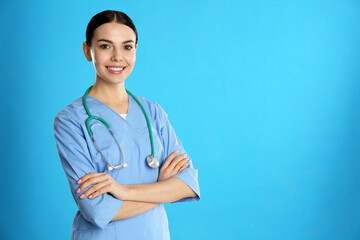 Wall Mural - Portrait of young doctor with stethoscope on blue background. Space for text