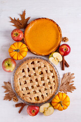 Wall Mural - Two traditional American Thanks Giving pies with apples, mini pumpkins & cinnamon sticks. Homemade fruit tarts baked to golden crust. Close up, copy space, top view, background.