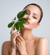 © Valua Vitaly - Beautiful woman with green leave near face and body.  Closeup girl's face with green leave. Skin care beauty treatments concept.