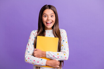 Canvas Print - Photo portrait of happy amazed schoolgirl hugging yellow book preparing for lesson smiling isolated on bright purple color background