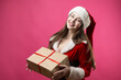 © Mountains Hunter - Beautiful young woman in Santa Claus costume against the red background.
