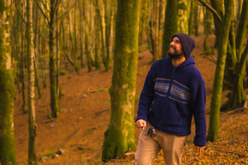 Wall Mural - Lifestyle, a smiling young man in blue wool sweater and a hat enjoying the forest in autumn. Artikutza Forest in San Sebastián, Gipuzkoa, Basque Country. Spain