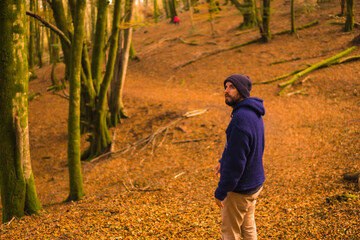 Wall Mural - Lifestyle, a smiling young man in blue wool sweater and a hat enjoying the forest in autumn. Artikutza Forest in San Sebastián, Gipuzkoa, Basque Country. Spain