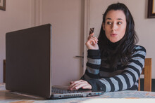 Una Mujer Joven Usa Un Ordenador Portátil Para Realizar Compras Por Internet Mientras Sostiene Una Tarjeta De Crédito Con Una Expresión De Sorpresa