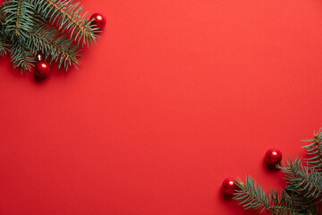 Christmas tree branches and red balls decoration on red background. Christmas greeting card, frame, banner mockup. Flat lay, top view, copy space.