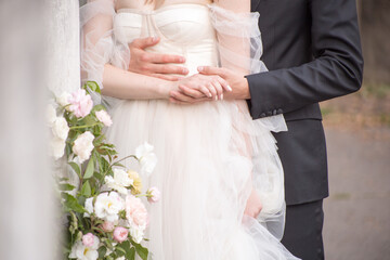 the groom stands behind the bride, hugs and holds her hand