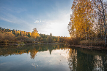 Wall Mural - autumn landscape, a beautiful forest on the banks of the river, the sunlight and the rays through ye