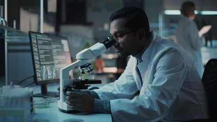 Wall Mural - Medical Research Scientist Conducts DNA Experiments Under a Microscope and Writes Results on Desktop Computer in a Biological Science Laboratory. Diverse Multiethnic Lab Engineer in White Coat.