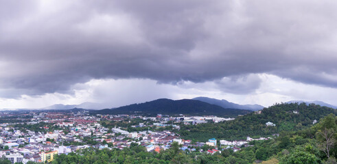 city view arial angle with storm cloud above mountain, huge dramatic rain coming from the mountain. dark cloudy day in tropical country scenery, panoramic landscape background