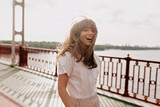 Fototapeta Krajobraz - Smiling romantic girl with long brown hair walking in sunshine in sunny day
