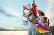 © New Africa - Happy parents and their children playing with kites outdoors at sunset. Spending time in nature
