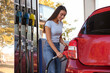 © New Africa - Young woman refueling car at self service gas station