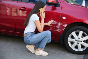 Wall Mural - Stressed woman talking on phone near car with scratch outdoors