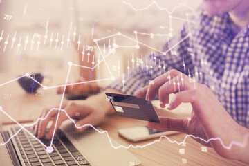 Double exposure of man hands holding a credit card and Forex graph drawing. Stock trading and digital fintech in Internet E-commerce concept.