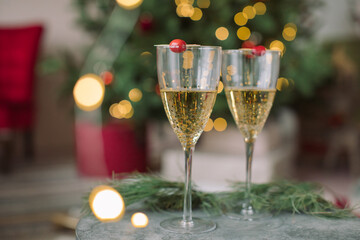 Christmas/New Year background with two glasses of champagne in front of decorated Christmas tree.