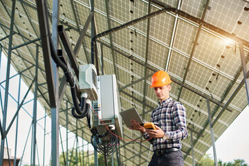 Male engineer working with laptop and sensor, on the background of the solar power station. Solar panels, sunny power electricity. Innovation future. Modern technology.