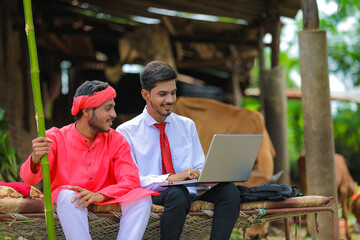 Wall Mural - Young indian agronomist showing some information to farmer in laptop at home