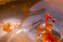 Orange Paint Splashing Into Water Creating Lots Of Paint Bubbles And Droplets And Other Effects.