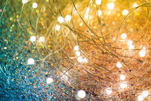 Twinkling Christmas Lights On A Shiny Background. Yellow-green Background With LEDs On A Wire Close-up