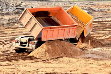 Wall Mural - modern truck unloads a large pile of sand from the body