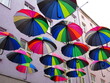 Kolorowe parasolki zawieszone między blokami wysoko nad ulicą