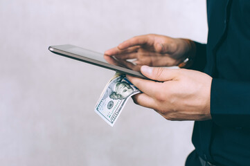 Tablet, money in a Man's hand. On a light background.