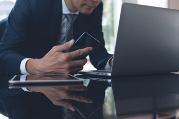 Poster - Businessman manager working on laptop computer using mobile phone  with digital tablet on office table