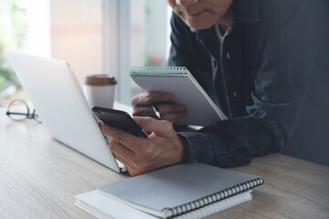 Poster - Casual business man using mobile phone working on laptop computer in office