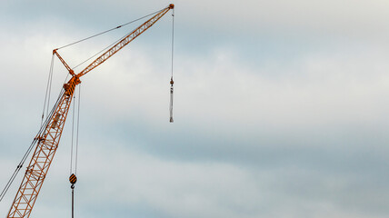 boom of a tower crane against a cloudy sky, minimalism