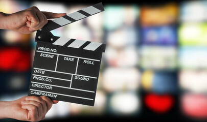 Clapperboard in hands on the background of TV screens