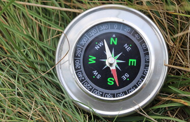 round compass on background of summer grass as symbol of tourism with compass, travel with compass and outdoor activities with compass