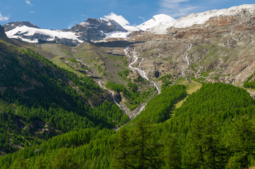 Snow-covered Kamel, Allalin, Feekopf, Alphübel mountain peaks behind the melting Fee Glacier and Felskin cablecar station on summer days is favourite destination for active travellers and adventurers