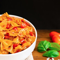 Healthy organic Italian Farfalle homemade fresh pasta spaghetti noodles cook with basil tomato garlic pepper sauce with vegan vegetarian recipe in white bowl on wooden vintage table