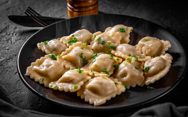 Wall Mural - Meat dumplings - russian pelmeni, ravioli with meat in black plate on Dark grey black slate background