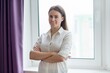© Valerii Honcharuk - Young confident smiling business woman, teacher, psychologist, coach, lawyer with folded hands near the window in office