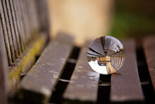 Beautiful Image With Lens Ball On A Wooden Bench Showing An Inverted Image In The Sphere. Space For Text.