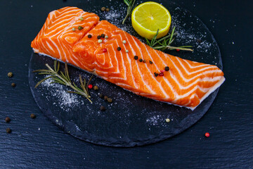 Raw salmon fillet with spices on black slate